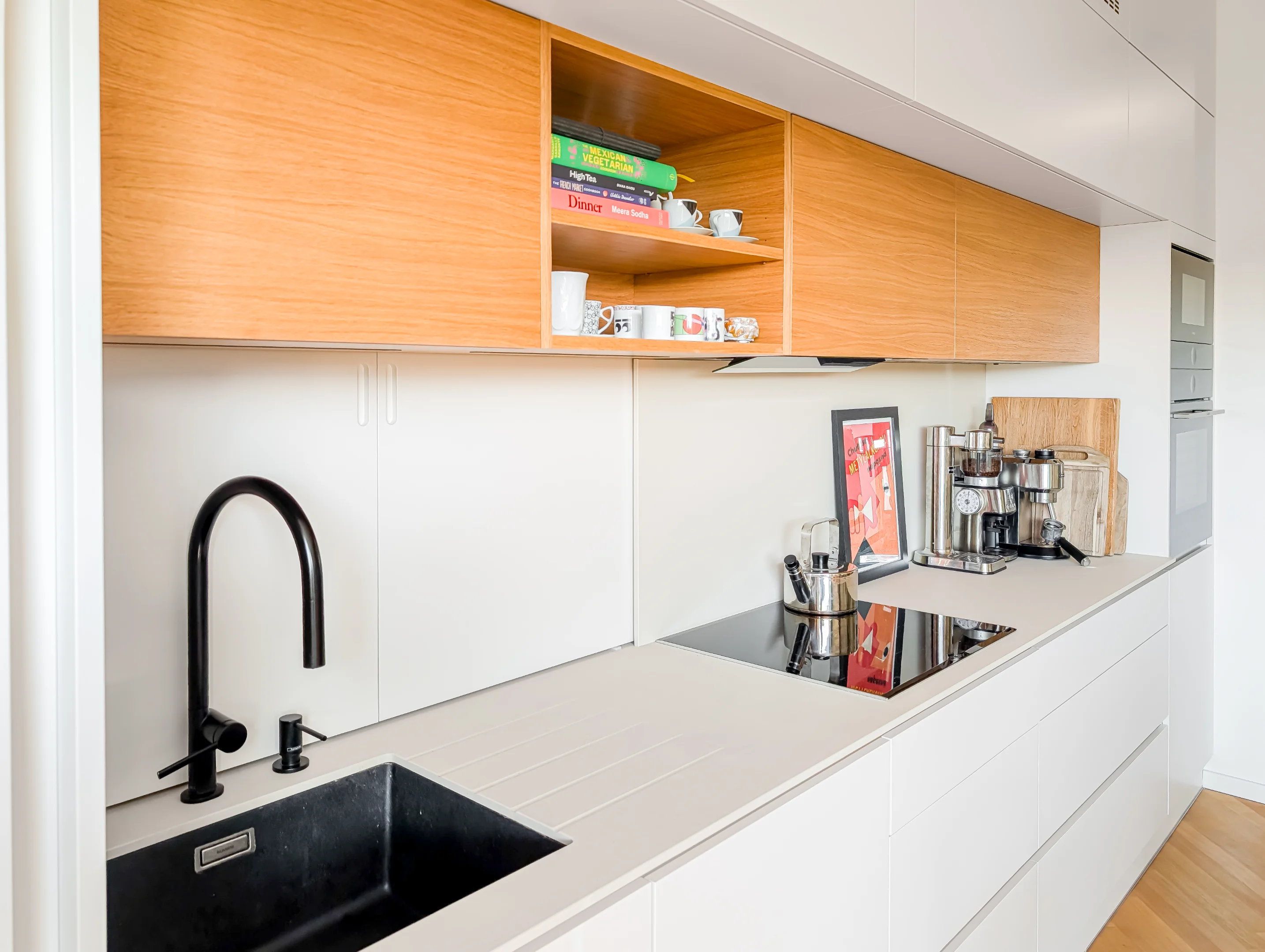 Moderní kuchyně: bílá linka, dřevěné skříňky, černá baterie.